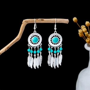 Detail of Bohemian dreamcatcher earrings with turquoise beads hanging on natural wood