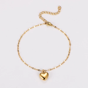 Detail of a golden stainless steel heart charm bracelet with shiny polished finish