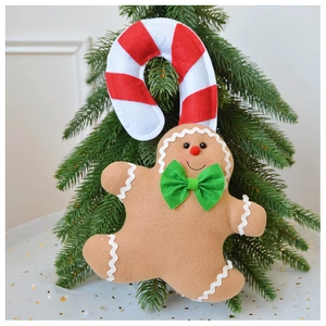 Detail of plush felt gingerbread man hanging on Christmas tree with red candy cane hook