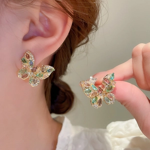 Macro shot of colorful butterfly stud earrings with sparkling crystals on a golden base
