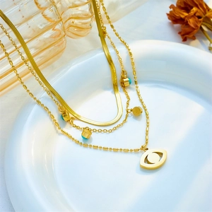 Multilayer gold chain necklace featuring turquoise beads and evil eye pendant on white plate