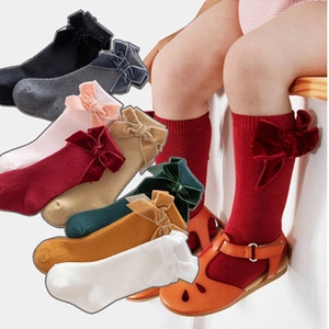 Detail showing velvet bows on multi-color cotton knit knee-high socks for toddlers