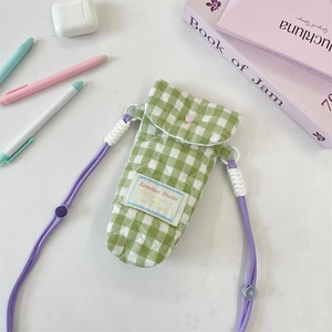 Detail of green and white quilted camera bag with heart button and woven purple strap