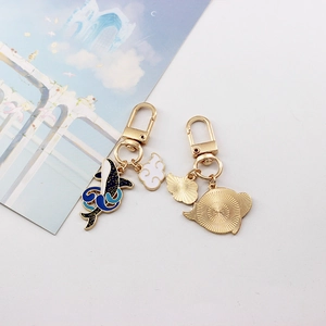 Detail of whale and shell enamel keychains with golden spring hooks and cloud charms