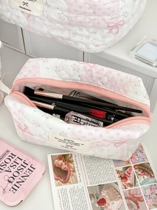 Detailed interior of a floral quilted makeup bag with pink bow showing large storage capacity
