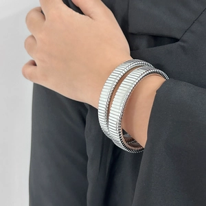 Detail of silver-tone stainless steel tubogas wrap bracelet on black suit sleeve