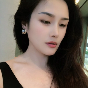 Minimalist 18K gold plated round pearl earrings worn by a model in soft lighting