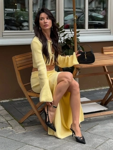 Detail of light yellow ribbed knit set featuring flare sleeves and a tied waist cardigan