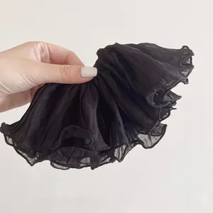 Detail of a large black chiffon scrunchie showing pleated ruffles and sheer texture
