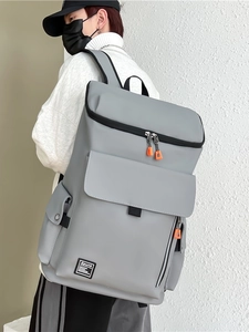 Grey urban backpack with orange accents shown from a side-back view on a model