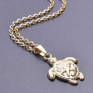 Macro view of a 18k gold turtle necklace pendant with intricate starfish shell textures
