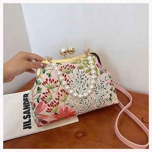 Detail der floralen Stickerei auf rosa Handtasche mit elegantem Perlen Griff