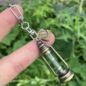 Detailed close-up of retro kerosene lamp keychain in bronze with glowing white particles