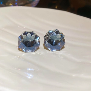 Macro shot of faceted blue crystal earrings on a textured white plate surface