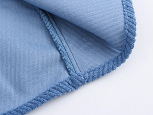 Close-up of light blue corduroy fabric featuring reinforced edges and stitching details