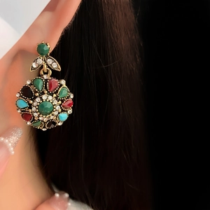 Detail of vintage flower earrings with colorful rhinestones on a bronze setting