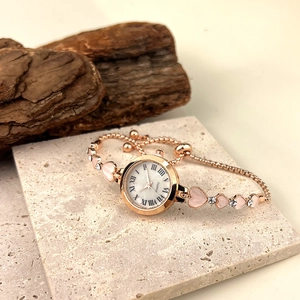 Gros plan d'une montre à quartz en or rose avec bracelet cœur et détails en strass