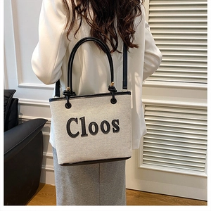 Detailed view of fashionable canvas tote bag worn over the shoulder by a model