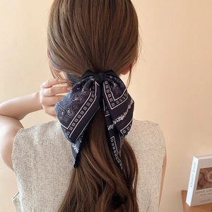 Detailed back view of a woman wearing a blue bow hair claw clip with paisley pattern