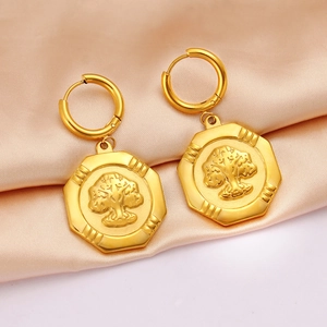 Golden octagonal drop earrings with tree relief on elegant pink silk background
