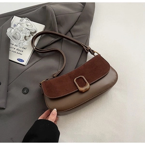 Detail of vintage brown suede stitching and antique bronze buckle on shoulder bag