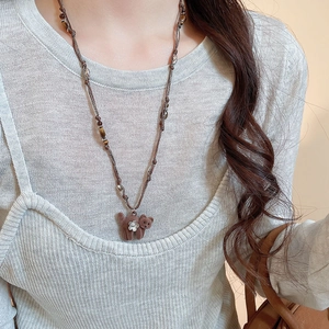 Detail der Vintage-Bärenkette mit Beflockung auf Strickpullover und mit Steinperlen