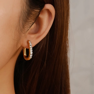 Elegant gold U-shaped earrings with round-cut cubic zirconia on a female model