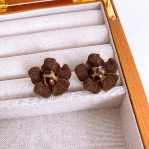 Close-up of brown felt flower earrings with leopard print center in a jewelry box