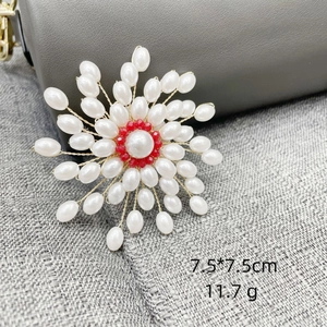 Detailed view of luxury pearl snowflake brooch with white pearls and red accent beads