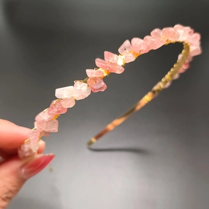 Detailed close-up of handmade golden wire headband with raw pink crystal stones