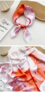 Close-up of orange and pink gradient silk scarf with smooth satin texture and rolled edges