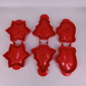Detail of red plastic snowflake and Christmas tree cookie molds on white background