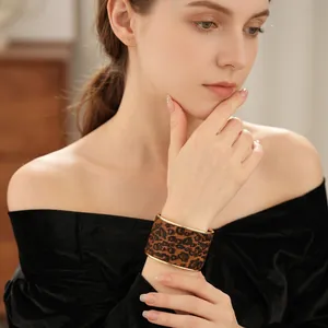 Luxurious wide leopard print cuff bracelet with gold-plated edges worn on female wrist
