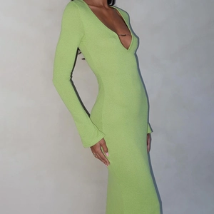 Détail du décolleté en V profond avec chaîne dorée sur une robe verte à manches longues
