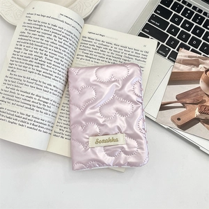 Close-up of pink heart-quilted fabric passport holder with Sozakka logo detail