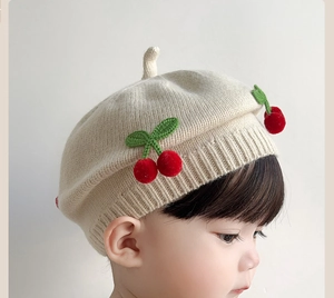 Close-up of knit baby beret with cute 3D red cherries and soft ribbed elastic edge
