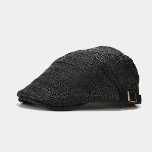 Close-up of black woven straw beret featuring adjustable metal buckle and textured weave