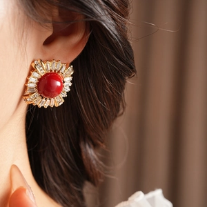 Detail of vintage sunburst stud earring with red gemstone and sparkling rhinestones