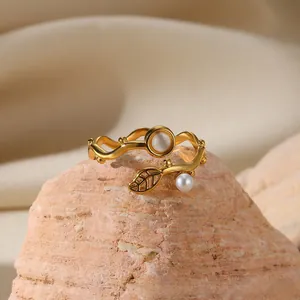 Detail of wavy gold ring with hollow leaf design, cat eye stone, and white pearl inlay