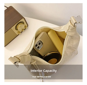 Internal capacity of beige crescent bag showing space for phone, lipstick and powder box