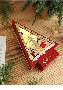 Close-up of wooden Christmas tree LED ornament with laser-cut reindeer and house pattern