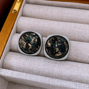 Détail macro de boucles d'oreilles léopard carrées avec feuilles d'or dans leur écrin
