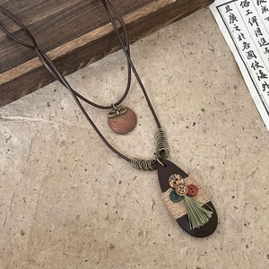 Close-up of bohemian water-drop wood pendant with twine, buttons, and green tassel detail.