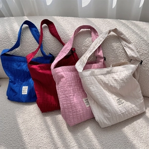 Detail of colorful pleated canvas tote bags with adjustable buckle straps on a sofa