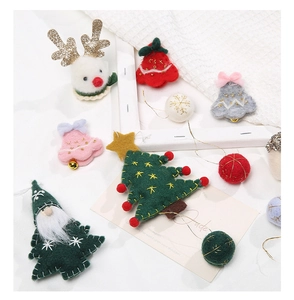Close-up of handmade felt Christmas ornaments with reindeer and tree on white fabric