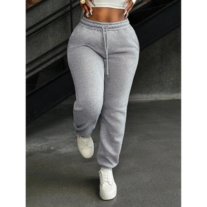 Women's loose grey joggers featuring high waist drawstring and cuffed ankles on grey steps