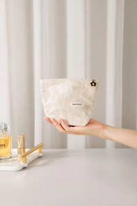 Détail de broderie florale sur sac en lin crème avec tirette de fermeture en fleur
