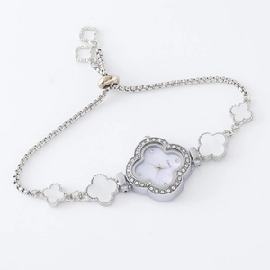 Detailed close-up of a silver four-leaf clover bracelet watch with a crystal square bezel