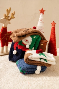 Close-up of thick coral fleece Christmas socks with 3D pompoms in festive colors
