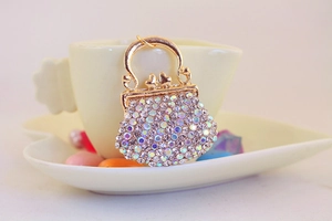 Close-up of golden alloy handbag keychain with shimmering rhinestones on a white cup